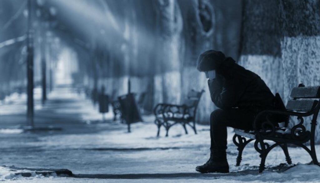 Sad woman sitting on a bench in winter time.