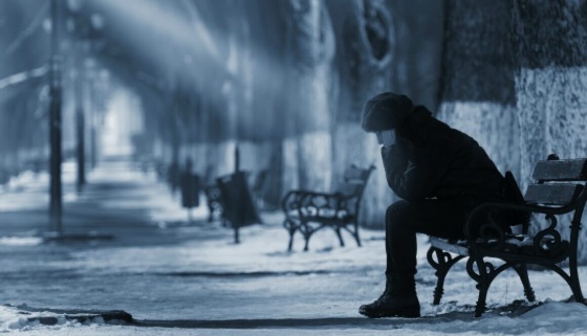 Sad woman sitting on a bench in winter time.