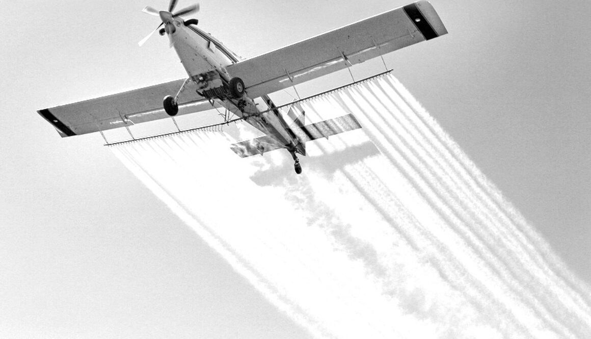 Airplane spraying insecticides over a farm field