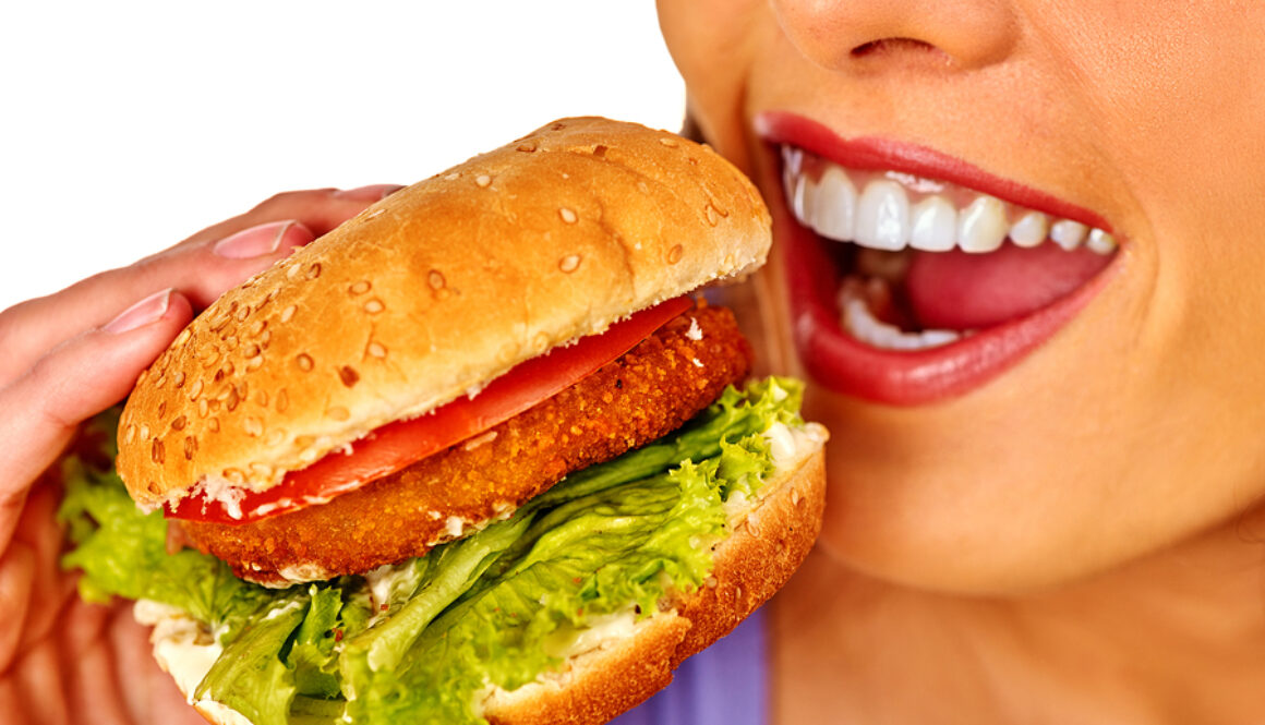 Girl eats big hamburger fast food. Fastfood concept.