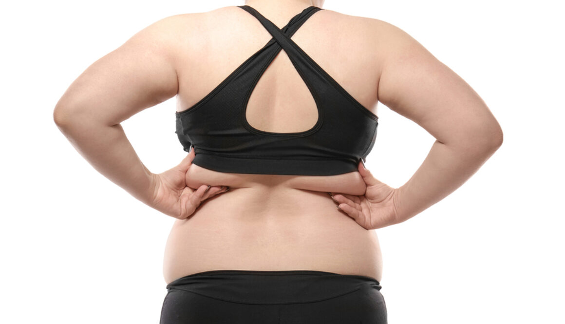 Woman touching fat on her back against white background. Weight